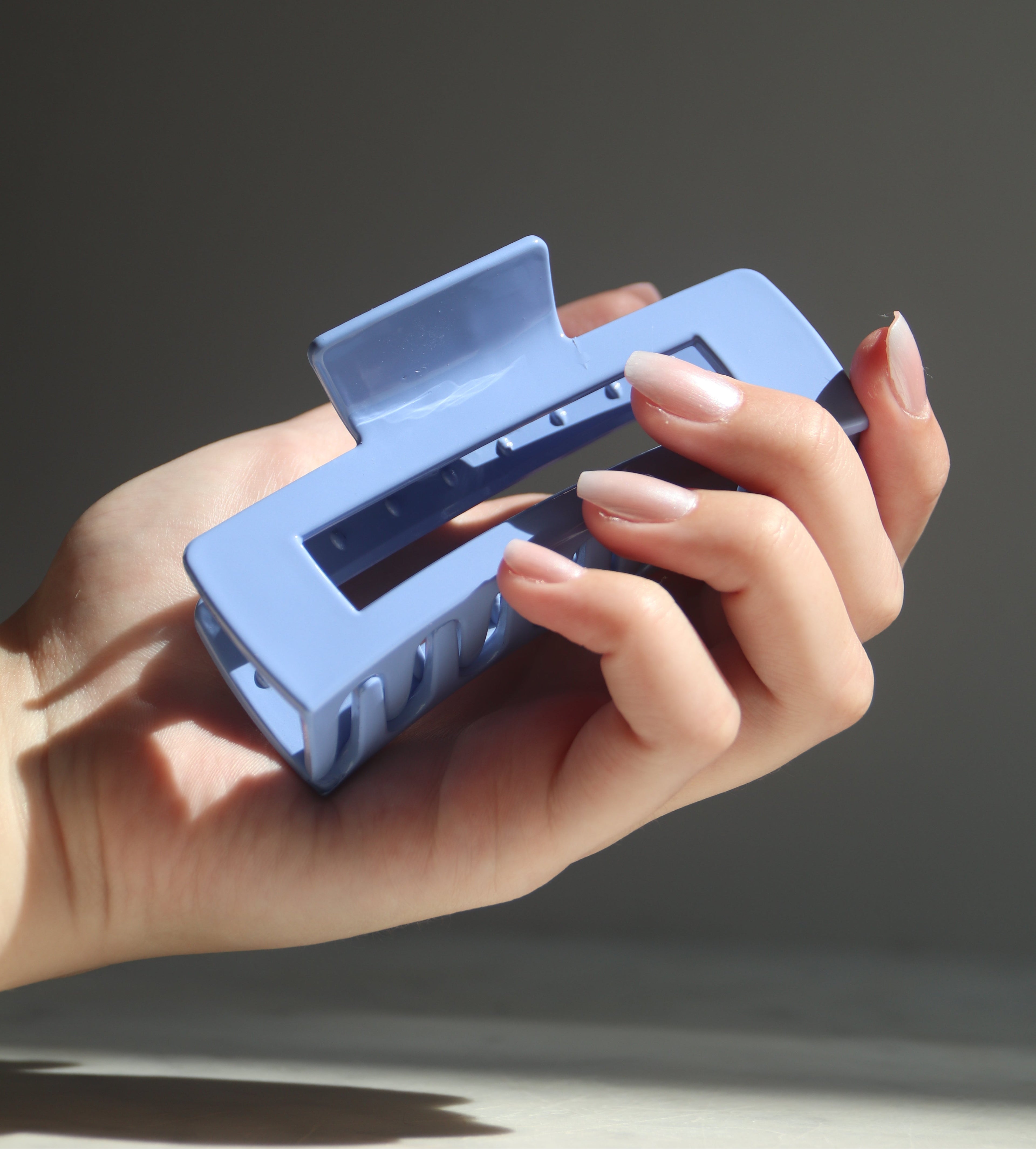 Hand holding a blue phone case against a dark background